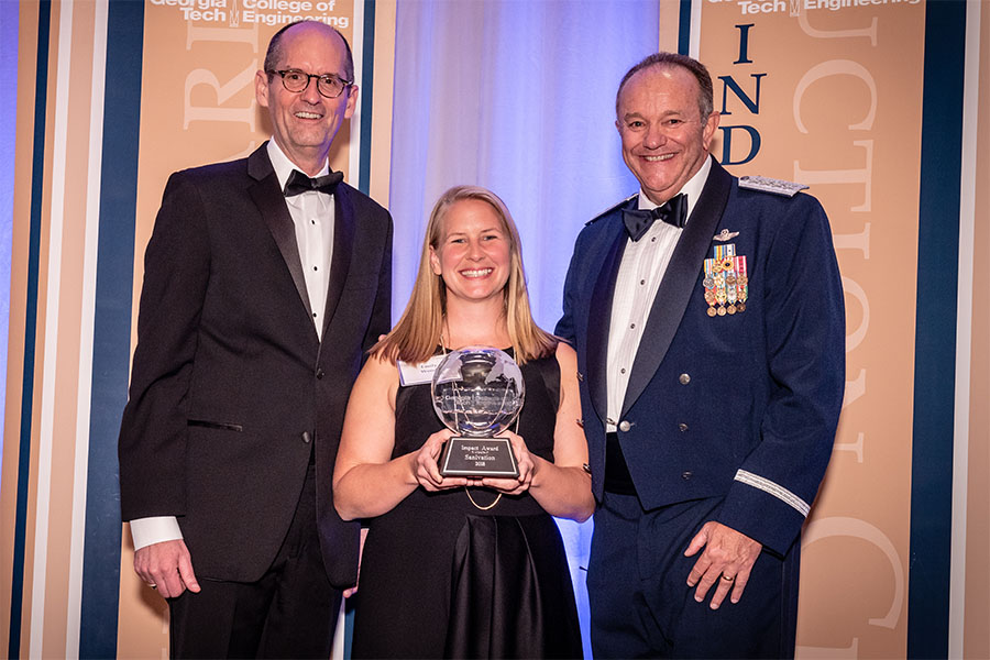 Emily Woods, center, one of the co-founders of Sanivation, with the first-ever Dean's Impact Award at the College of Engineering Alumni Awards and Induction Ceremony April 21. Woods created Sanivation with environmental engineering alumnus Andrew Foote. She's with engineering Dean Steve McLaughlin, left, and the ceremony's guest speaker, retired Gen. Philip Breedlove. (Photo: Gary Meek)