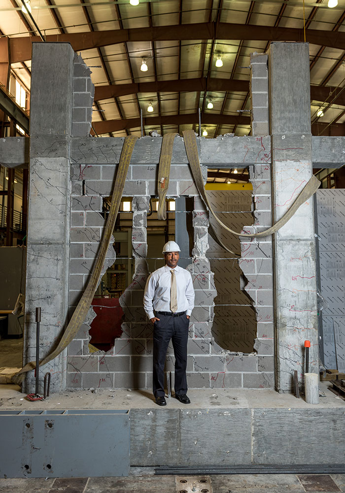 Reginald DesRoches stands with the ruptured cinder block wall one of his Ph.D. students destroyed while testing different kinds of masonry infill designed to strengthen similar structures in the Caribbean. DesRoches will draw on decades of earthquake research like this for the University of California, Davis, College of Engineering distinguished lecture he'll deliver in September. (Photo: Rob Felt)