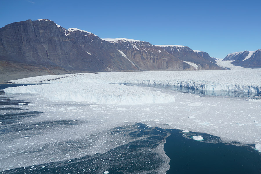 An iceberg floats in a fjord in Greenland. Researchers believe it broke off the nearby glacier when a powerful tsunami ripped through the fjord. Right: An iceberg sits in the middle of a house in Nuugaatsiaq, Greenland. (Photo: Hermann Fritz)