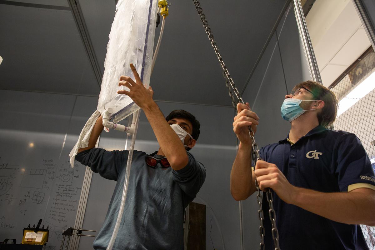 Two students lower a block of ice into the holding tank