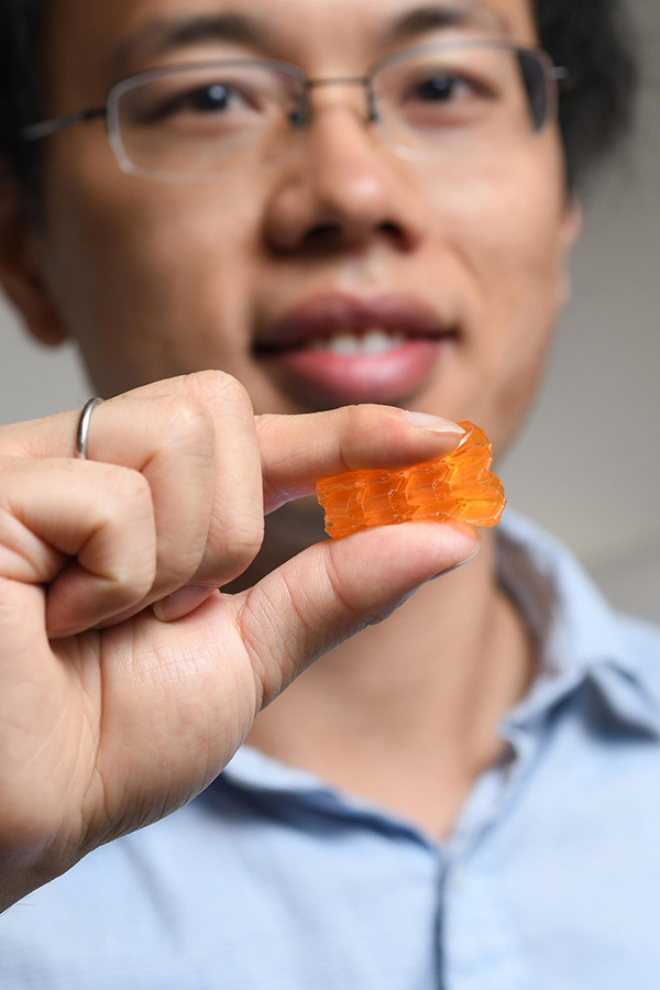 Georgia Tech postdoctoral fellow Xiao Kuang demonstrates the compressibility of origami structures created through Digital Light Processing 3D printing. (Photo: Christopher Moore)