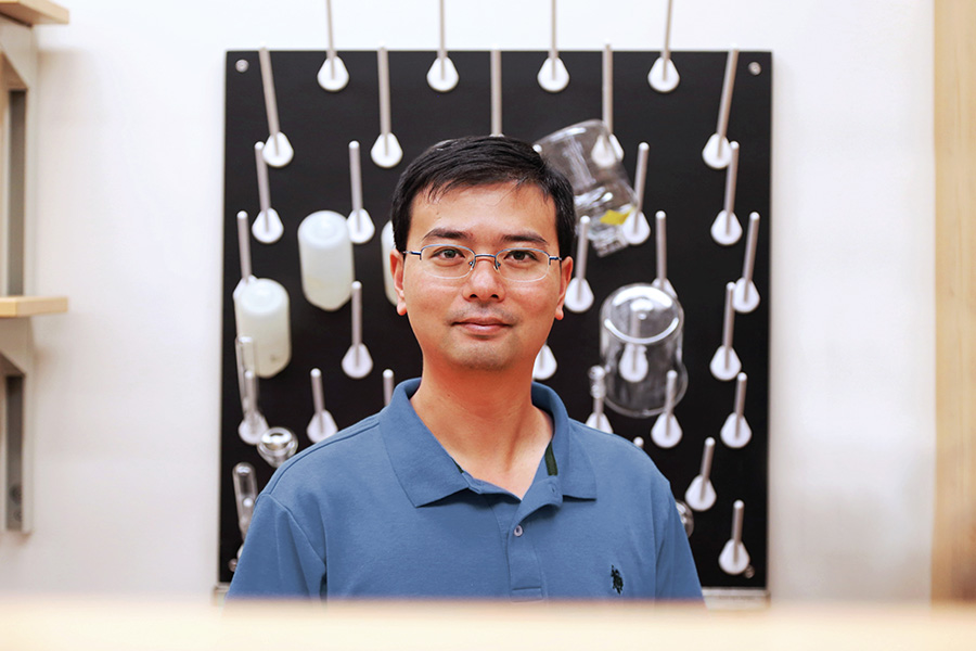 Xing Xie in his lab with a variety of beakers and bottles on a drying rack in the background. (Photo: Jess Hunt-Ralston)