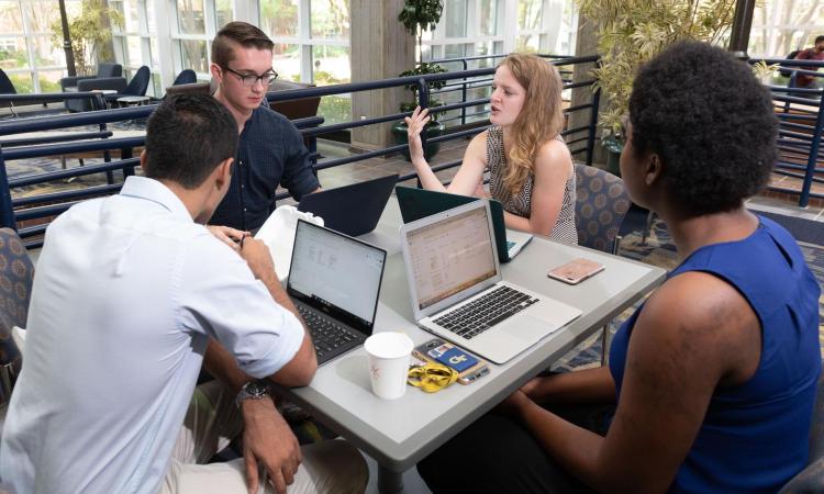 Diverse group of students working on laptops at a table