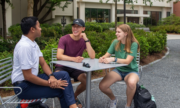 Students sitting and talking at a table outside