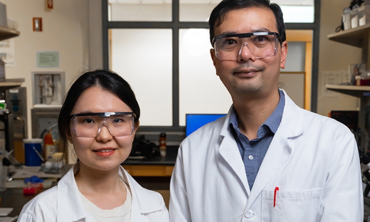 A man and woman wearing lab coats and goggles