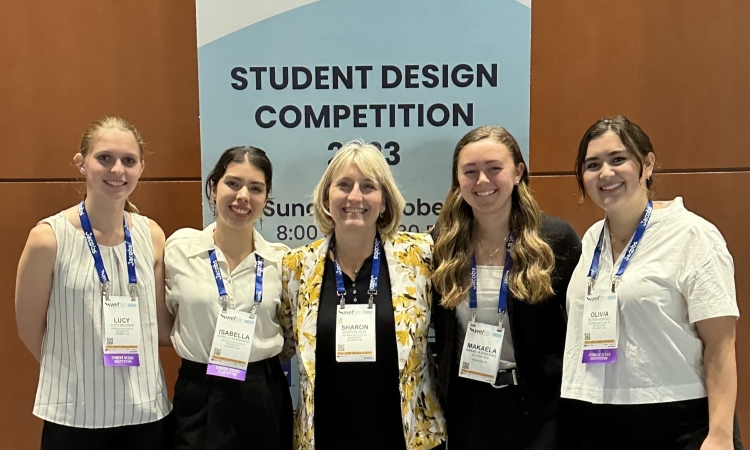 Five women post in front of a sign reading Student Design Competition 