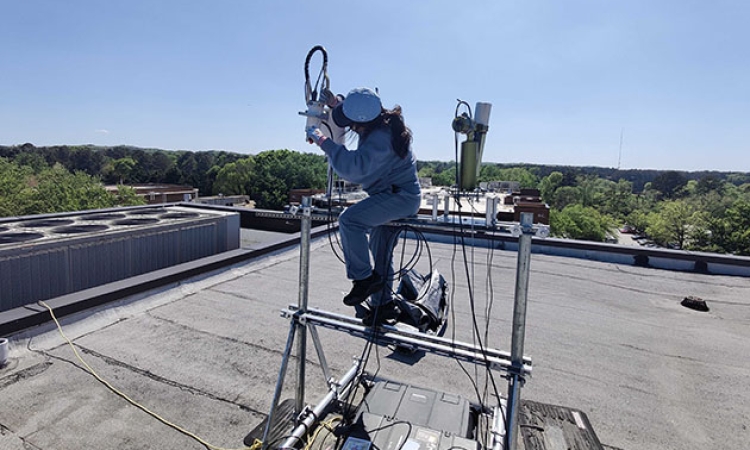 Yakun Zhou, CEE Ph.D. student, installs a Pandora instrument on the roof of Perimeter College-Georgia State University.