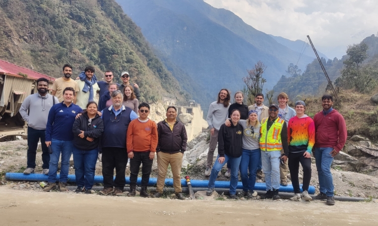 A group poses in front of mountains 