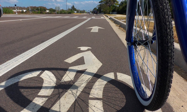 A bicyclist rides in a marked bike lane alongside a multi-lane road in Lutz, Florida. A new study of bicycle infrastructure from a team of School of Civil and Environmental Engineering researchers has found we don’t know much yet about how well bicycle infrastructure like these lanes protect riders. (Photo Courtesy: Daniel Oines via Flickr.)