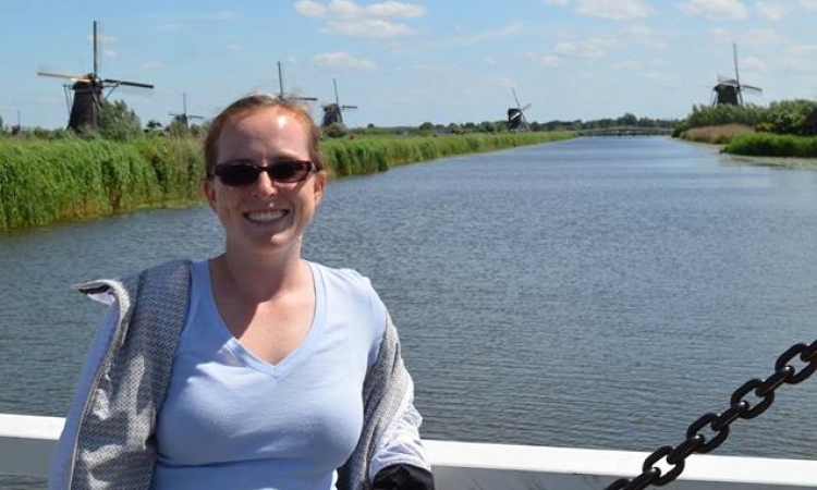 Ph.D. student April Gadsby stands on a bridge over a canal in the Netherlands in 2017 with a few of the country's famed windmills in the background. (Photo Courtesy: April Gadsby)