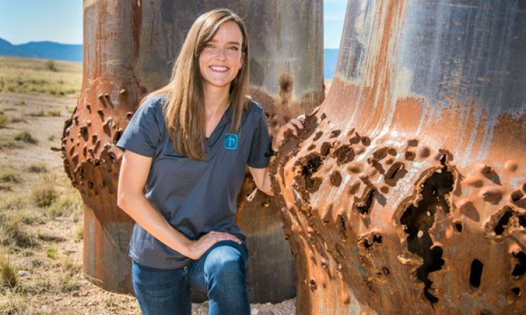 Ph.D. student and Sandia National Labs intern Rebecca Nylen kneels next to blasted steel cylinders, some of her handy work as a computational shock physicist. (Photo: Randy Montoya, Sandia National Laboratories)