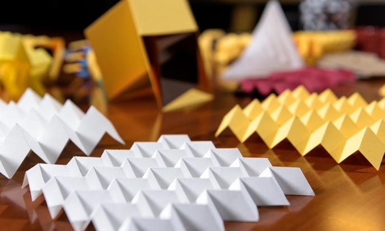 Paper origami models demonstrate various folding patterns that can be useful in engineering applications. In the foreground is a sheet in the Miura-ori pattern. (Photo: Rob Felt)