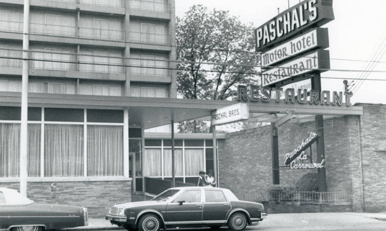 A black and white vintage photo of cars parked in front of the marquee sign for Paschal's Motor Hotel and Restaurant 