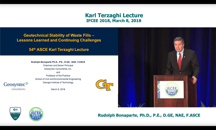 Video screenshot of Rudy Bonaparte delivering the Karl Terzaghi Lecture on March 8, 2018. Split screen shows Bonaparte at a podium on the right and his title slide on the left, "Geotechnical Stability of Waste Fills – Lessons Learned and Continuing Challenges."