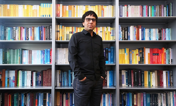 Arash Yavari stands in front of shelves stacked with colorful books