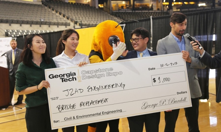 Team J2AD Engineering won the civil and environmental engineering award at the fall 2017 Capston Design Expo. From left, Jessie Lei, Jiyoon Oh, Austin Foo and Donald Smith accept their winnings from Buzz (yellow jacket, center). (Photo: Jess Hunt-Ralston)