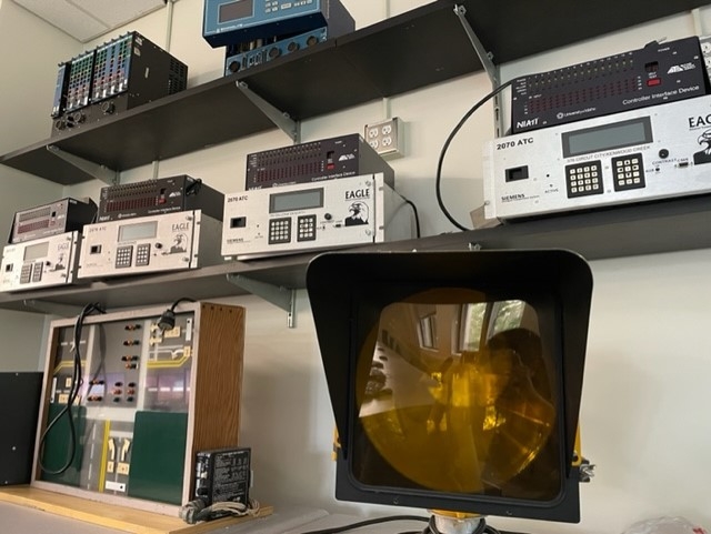 A yellow traffic light on a shelf next to silver machinery