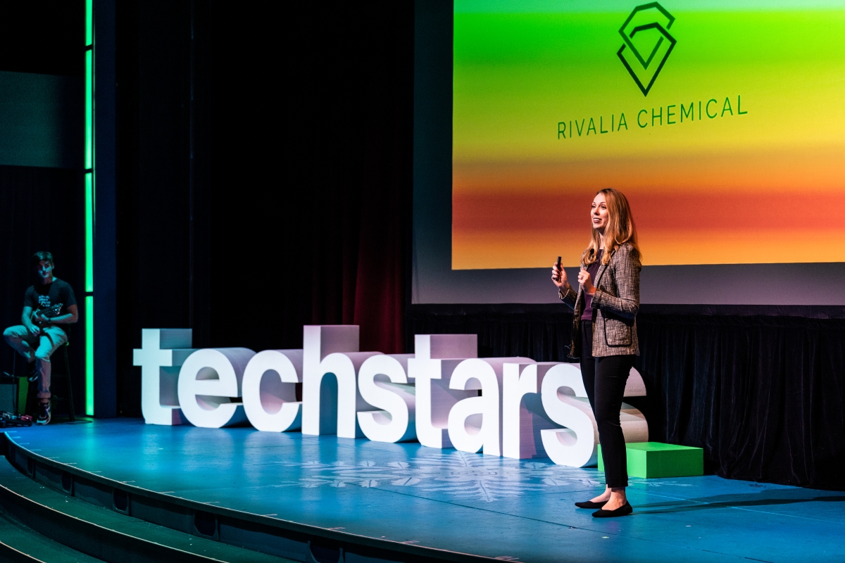 A woman standing on stage in front of letters that spell "techstars"