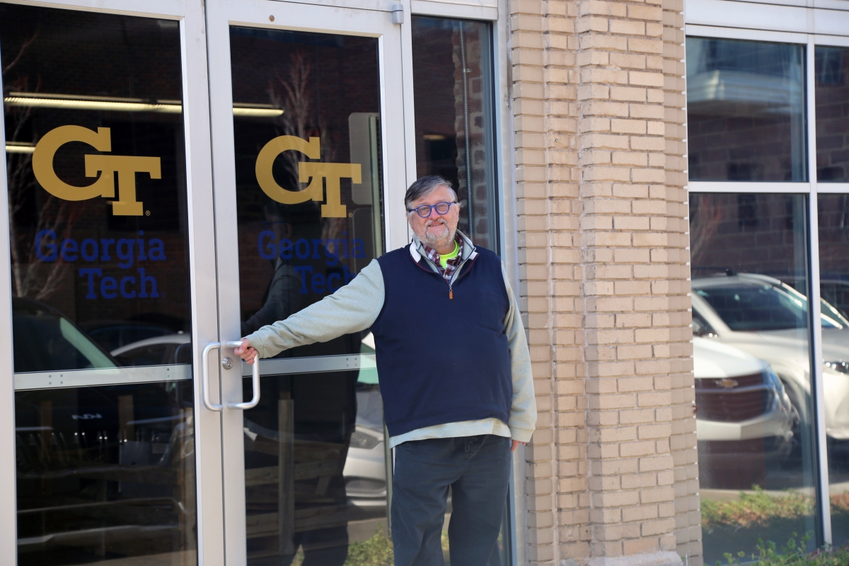 A man stands in front of double doors with the Georgia Tech logo on the glass