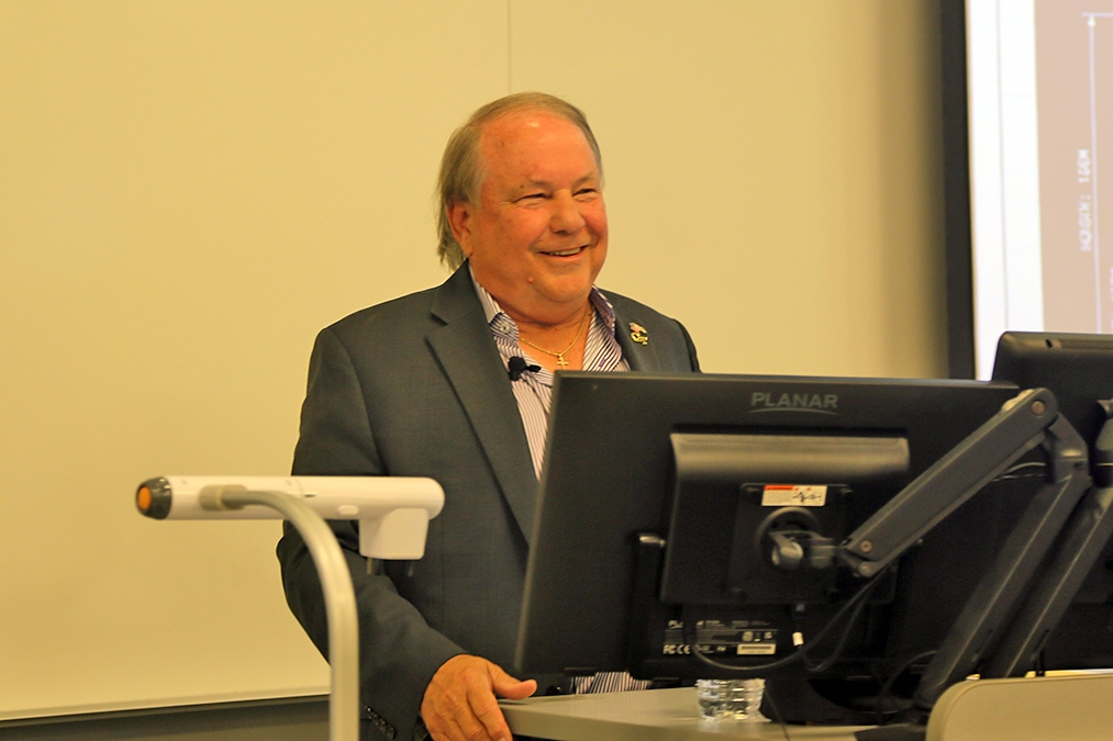 John Carroll in a navy blue suit coat and a lavender shirt