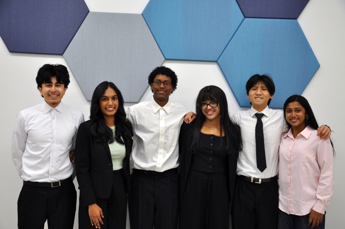 A group of six people posing in front of blue hexagonal tiles 