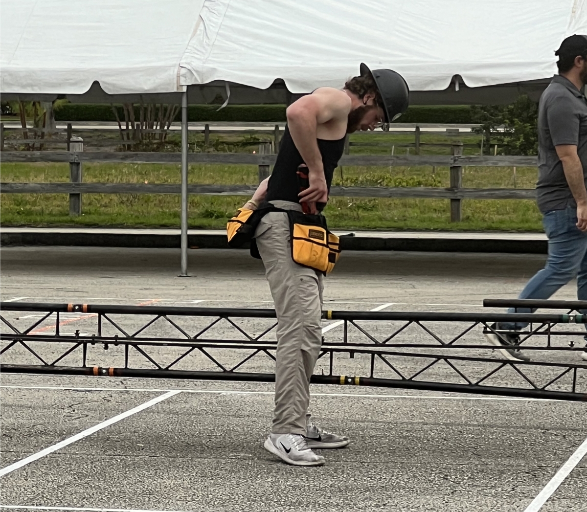 Member of the GT-ASCE Steel Bridge team in a black tank and beige pants working on assembling the bridge.