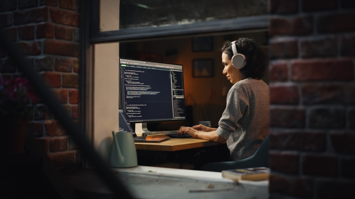 A woman wearing headphones sitting in front of a computer screen