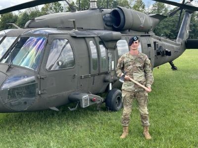 Mason Ladd in infantry military uniform standing in front of a military helicopter
