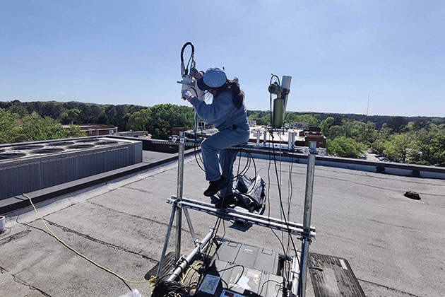 Yakun Zhou, CEE Ph.D. student, installs a Pandora instrument on the roof of Perimeter College-Georgia State University.