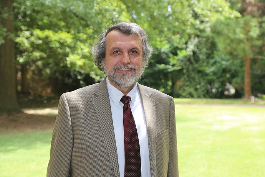 Michael Rodgers poses in a coat and tie with trees in the background