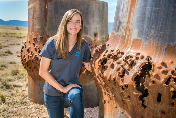 Ph.D. student and Sandia National Labs intern Rebecca Nylen kneels next to blasted steel cylinders, some of her handy work as a computational shock physicist. (Photo: Randy Montoya, Sandia National Laboratories)