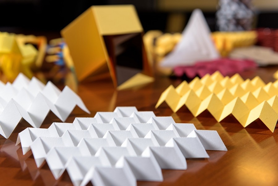 Paper origami models demonstrate various folding patterns that can be useful in engineering applications. In the foreground is a sheet in the Miura-ori pattern. (Photo: Rob Felt)
