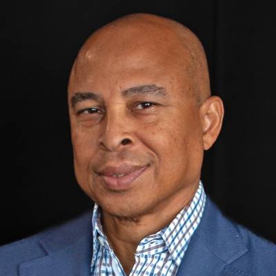 Portrait of Carlyle Bernard in a blue blazer and patterned grey, white and blue dress shirt